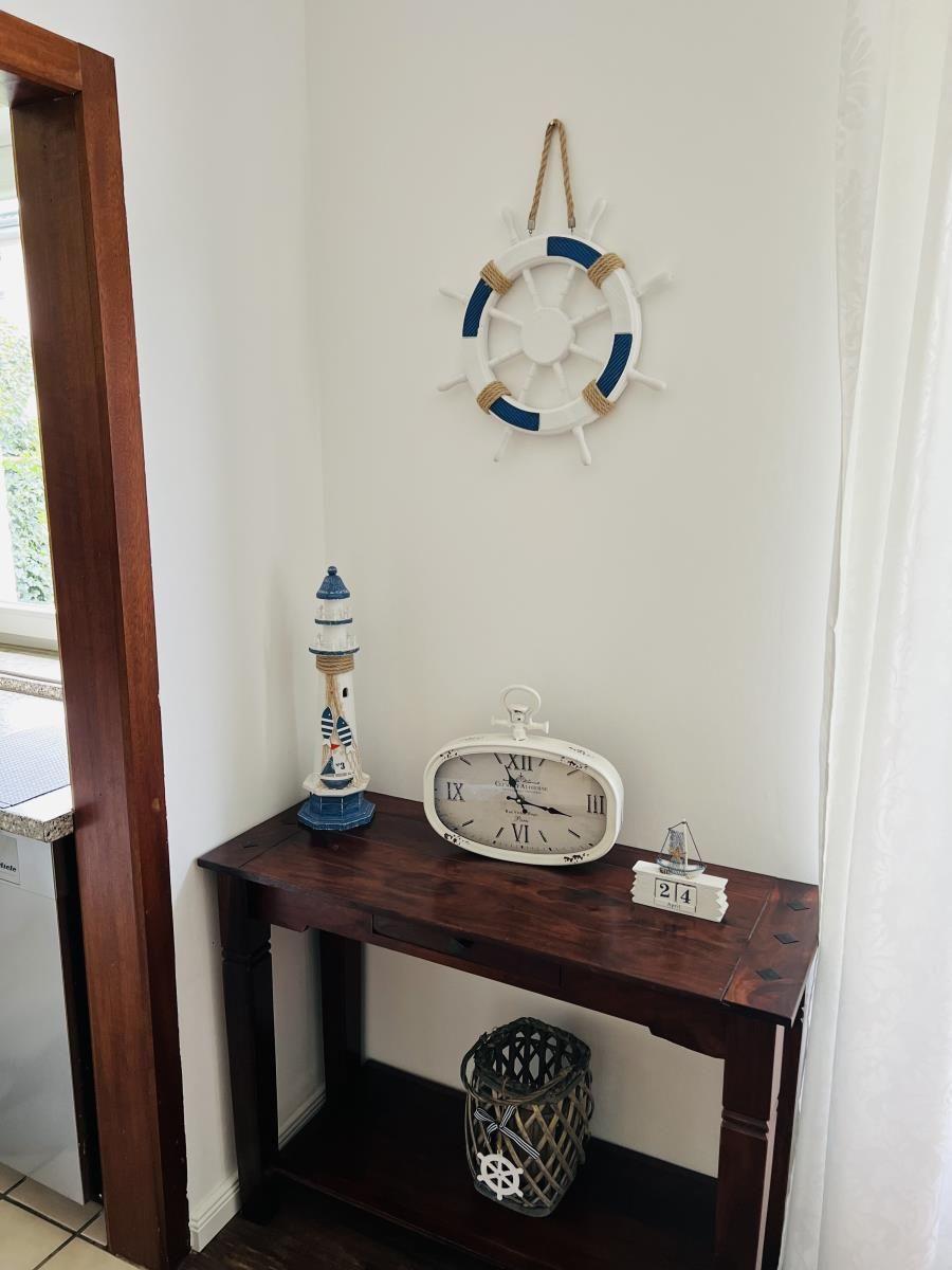 Eingangsbereich mit Tisch, Uhr, Leuchtturm und Steuerraddekoration.
