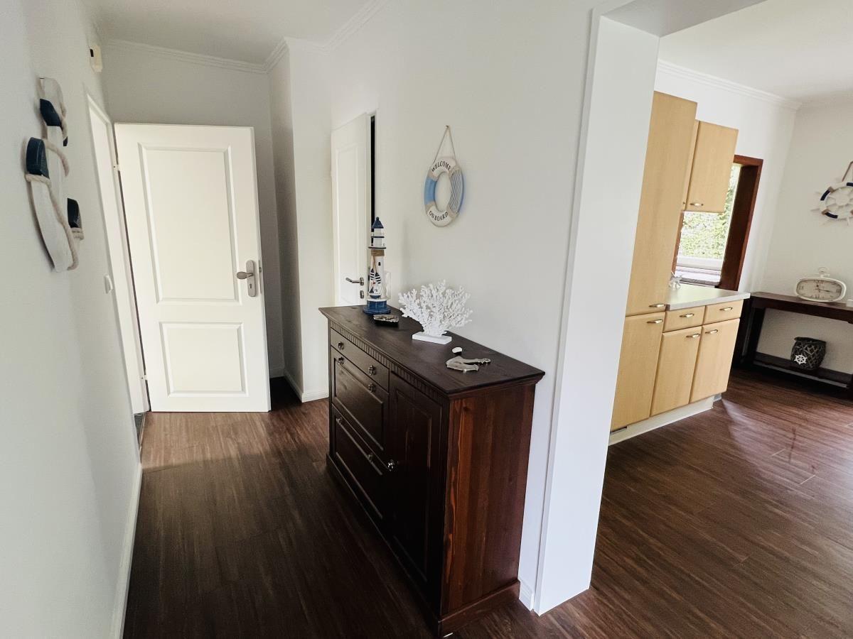 Eingangsbereich mit dunklem Schrank und Küchenbereich im Hintergrund.