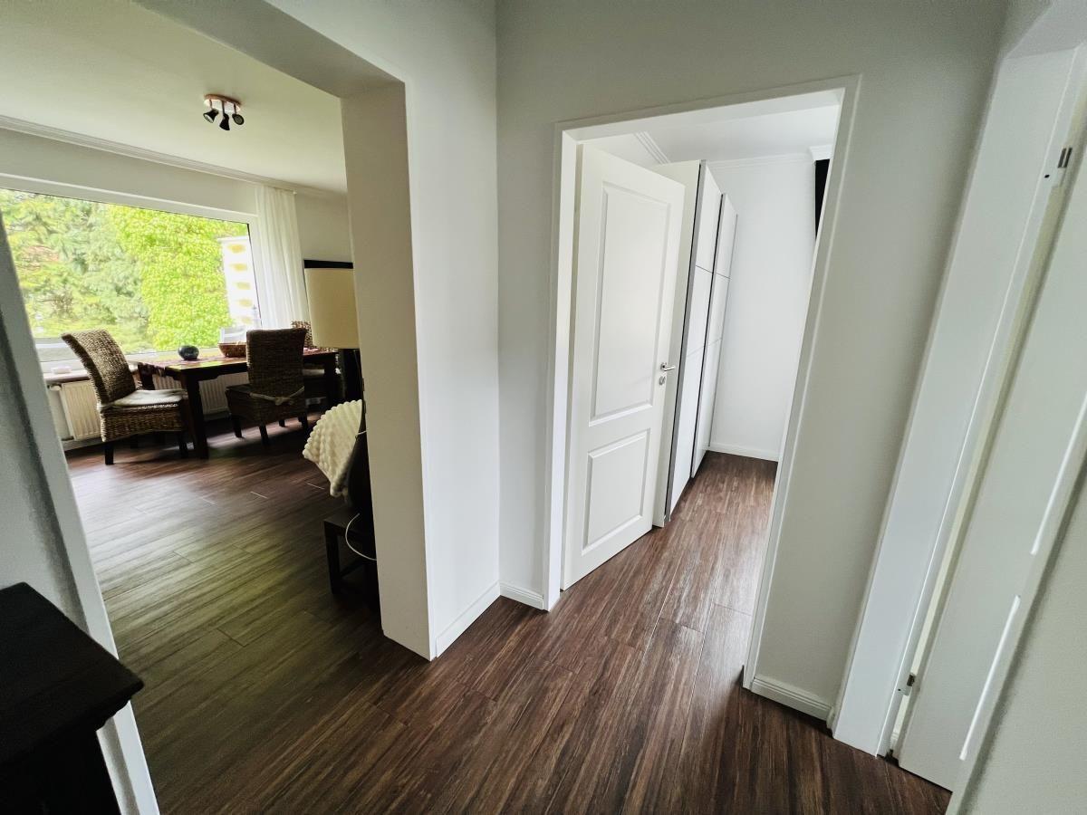 Flur mit Holzboden, Tür zu Schlafzimmer und Blick in Esszimmer mit Tisch und Stühlen.