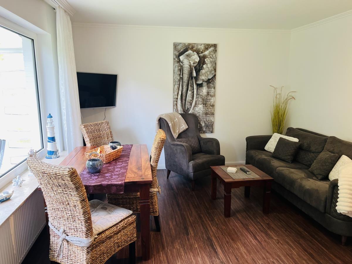 Wohn- und Essbereich mit Sofa, Sessel, Esstisch und Wandbild.