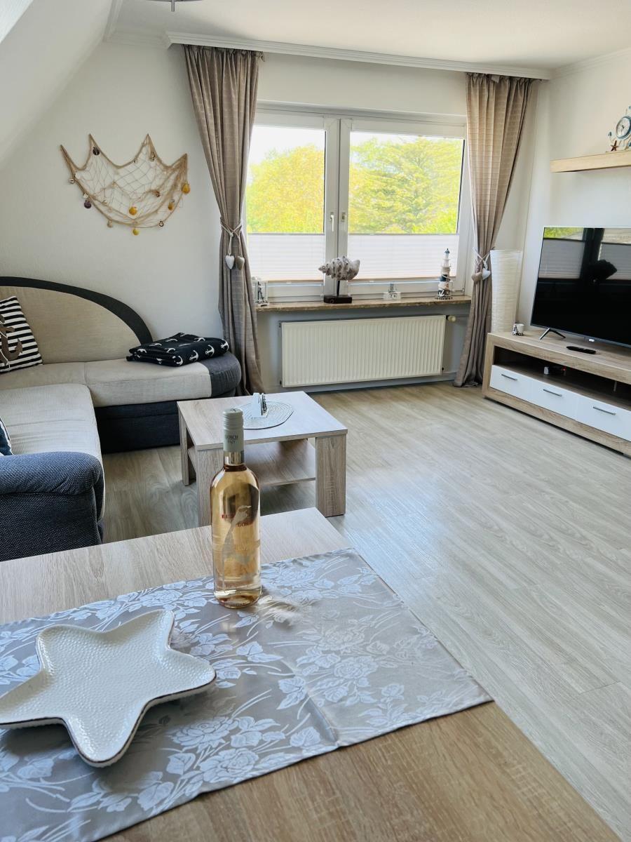 Living room with sofa, TV, and window overlooking trees.