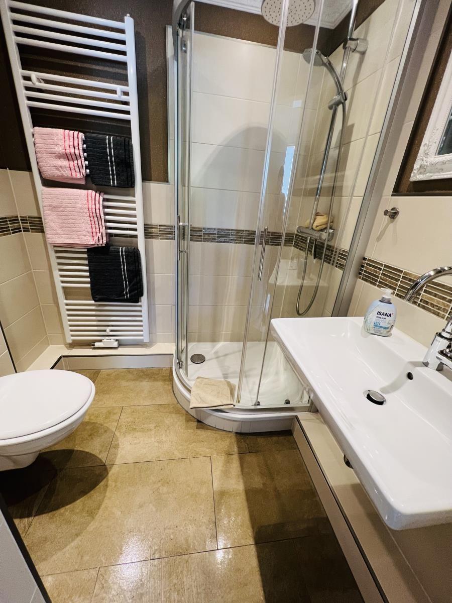 Bathroom with shower, sink, and towel warmer with towels.