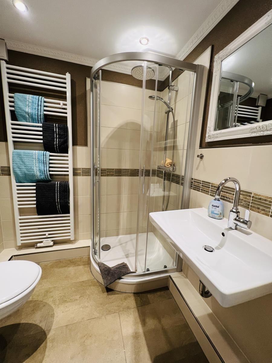 Bathroom with shower, sink, and towel radiator with towels.