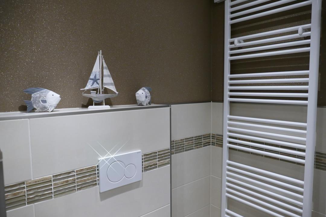 Bathroom with heater, toilet, and decorative fish and sailboat.