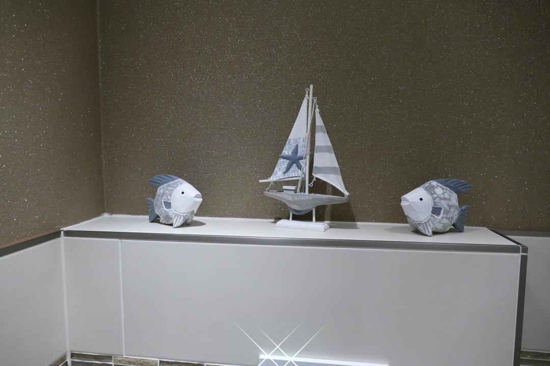 On a shelf are two fish figurines and a sailboat model.