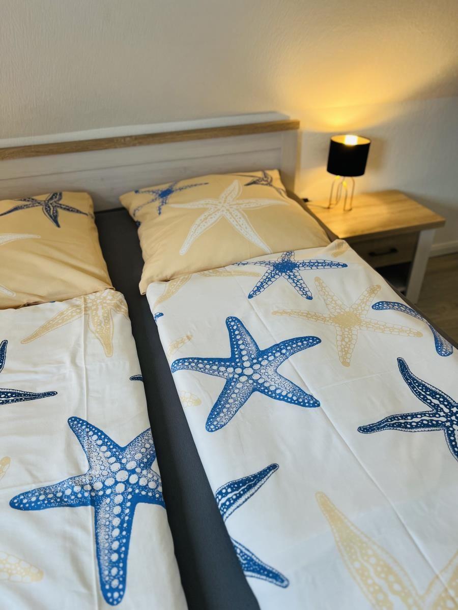 Double bed with starfish pattern, nightstand, and lamp