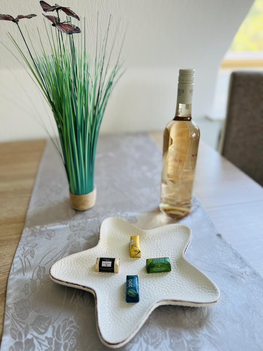 Table with bottle, chocolates, and plant. Star-shaped dish with sweets.