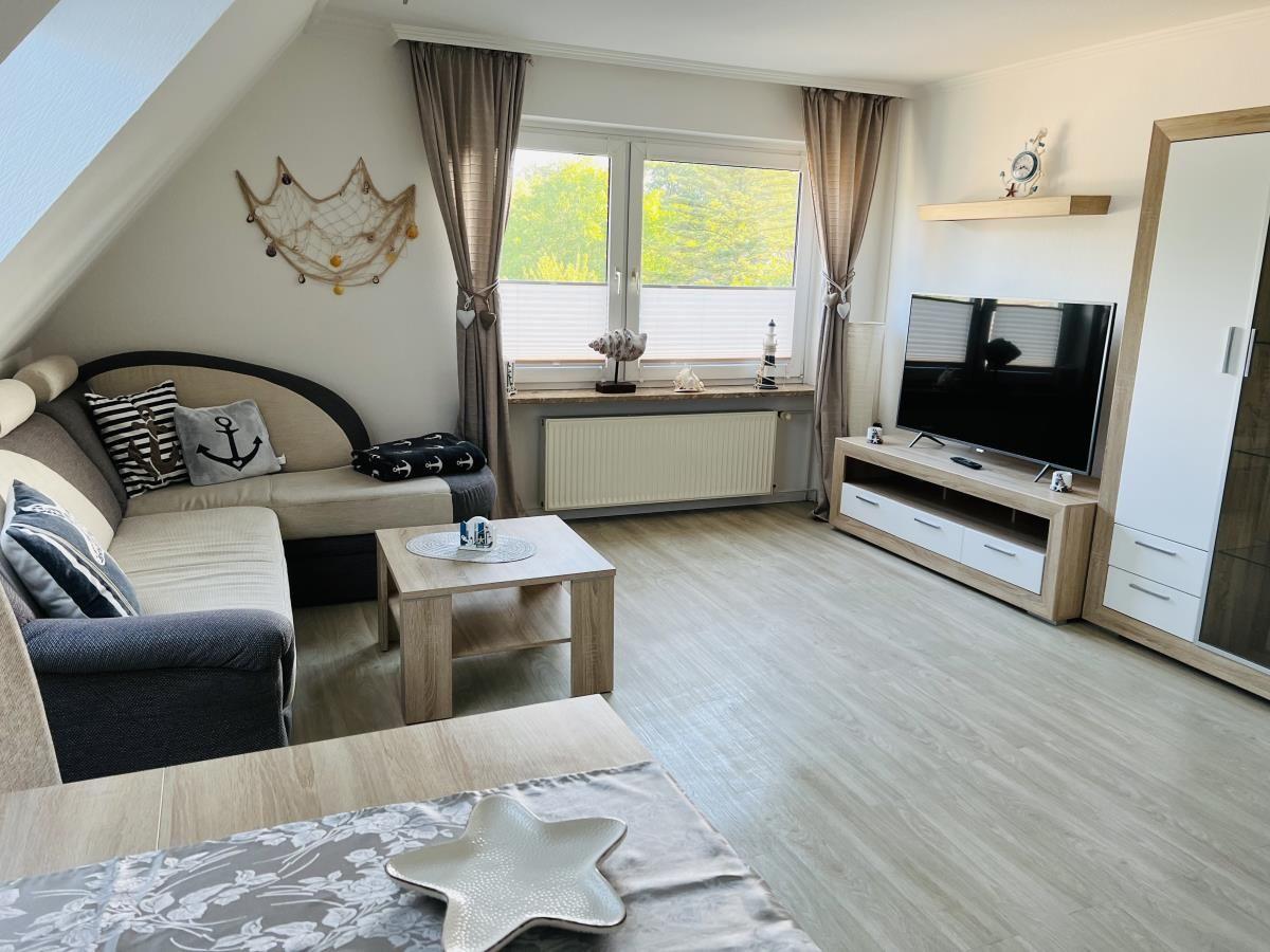 Living room with sofa, TV, and window with view of greenery.
