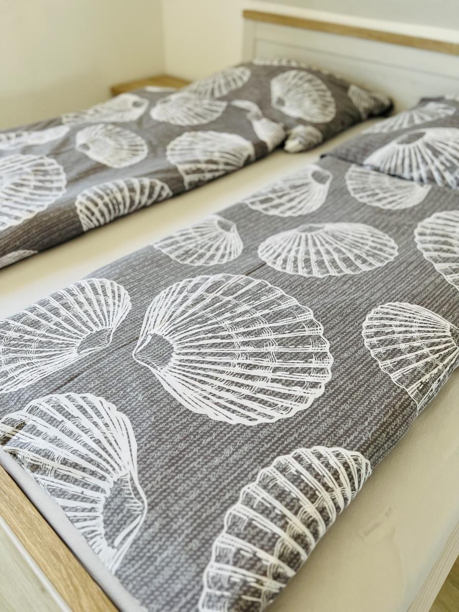 Two beds with gray bedspread featuring shell pattern.