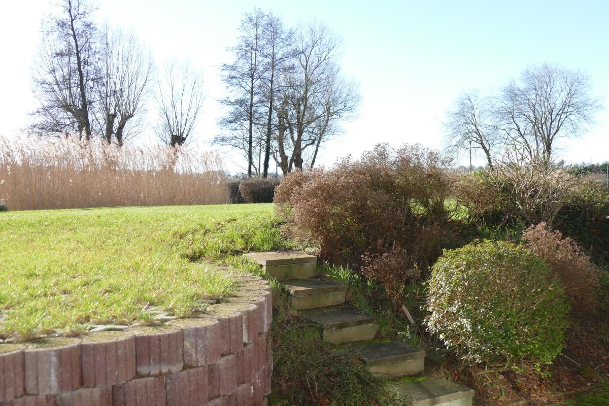 Steinstufen führen durch einen Garten mit Gras, Sträuchern und Bäumen.