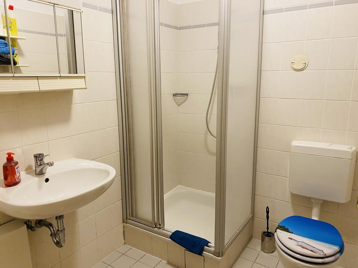 Badezimmer mit Dusche, Waschbecken und Toilette.