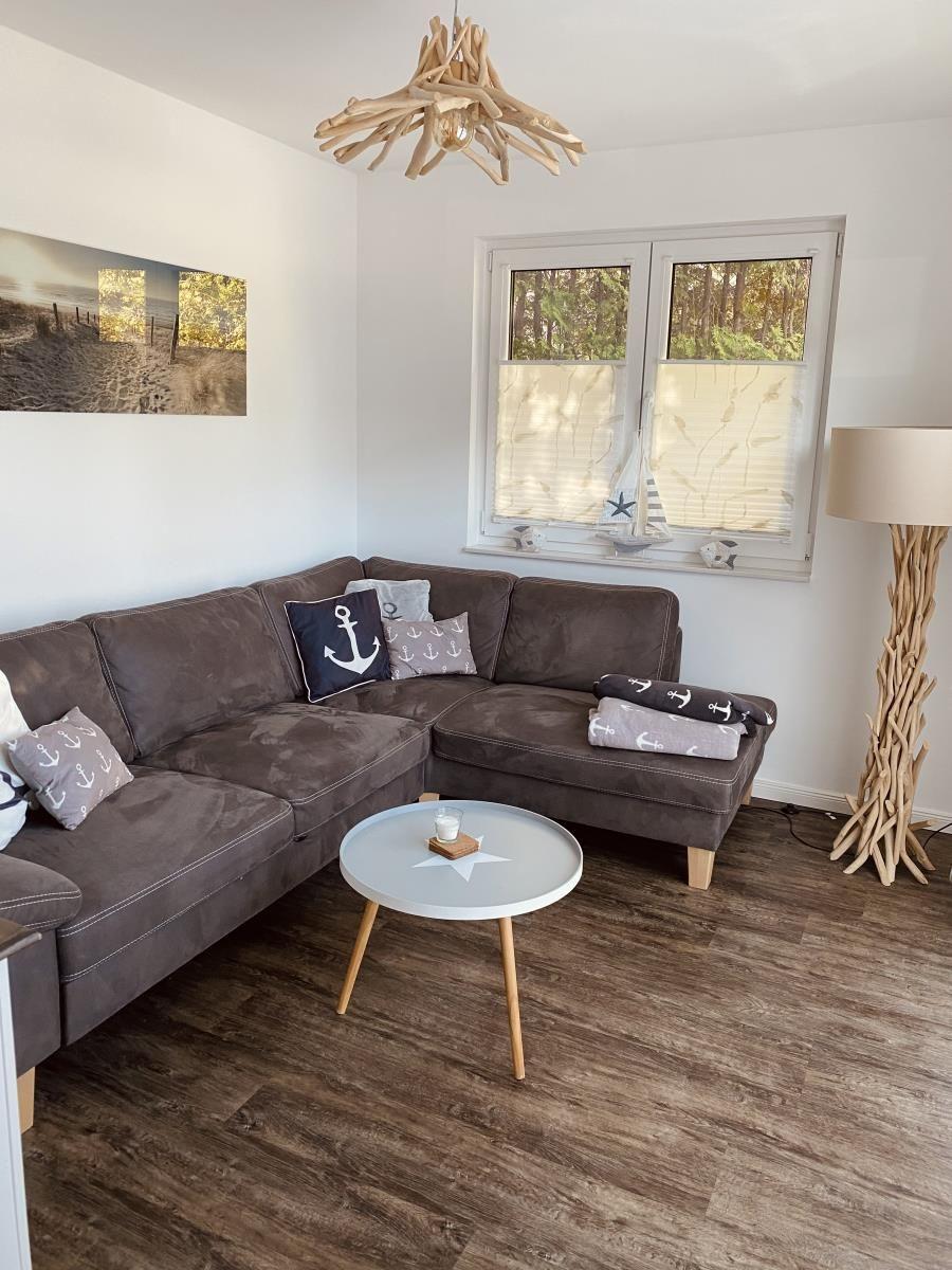 Ein Wohnzimmer mit braunem Sofa, runden Tisch und Fenster mit Jalousie.