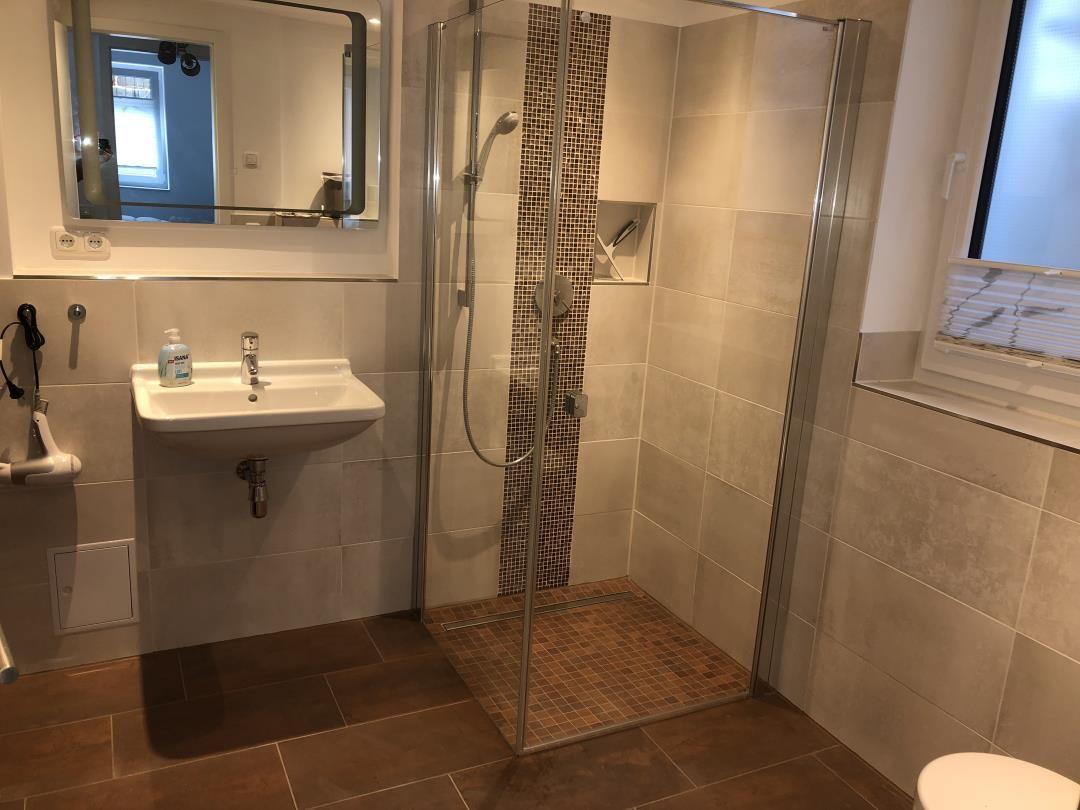 Badezimmer mit Dusche, Waschbecken und Spiegel