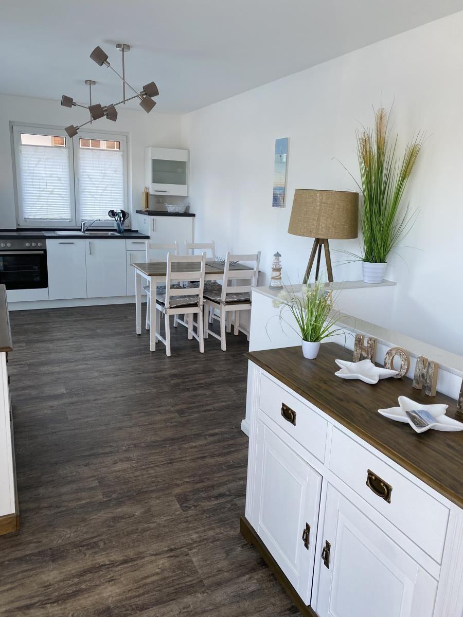 Küche mit Essbereich und Wohnbereich. Holzboden, weiße Möbel, moderne Beleuchtung.