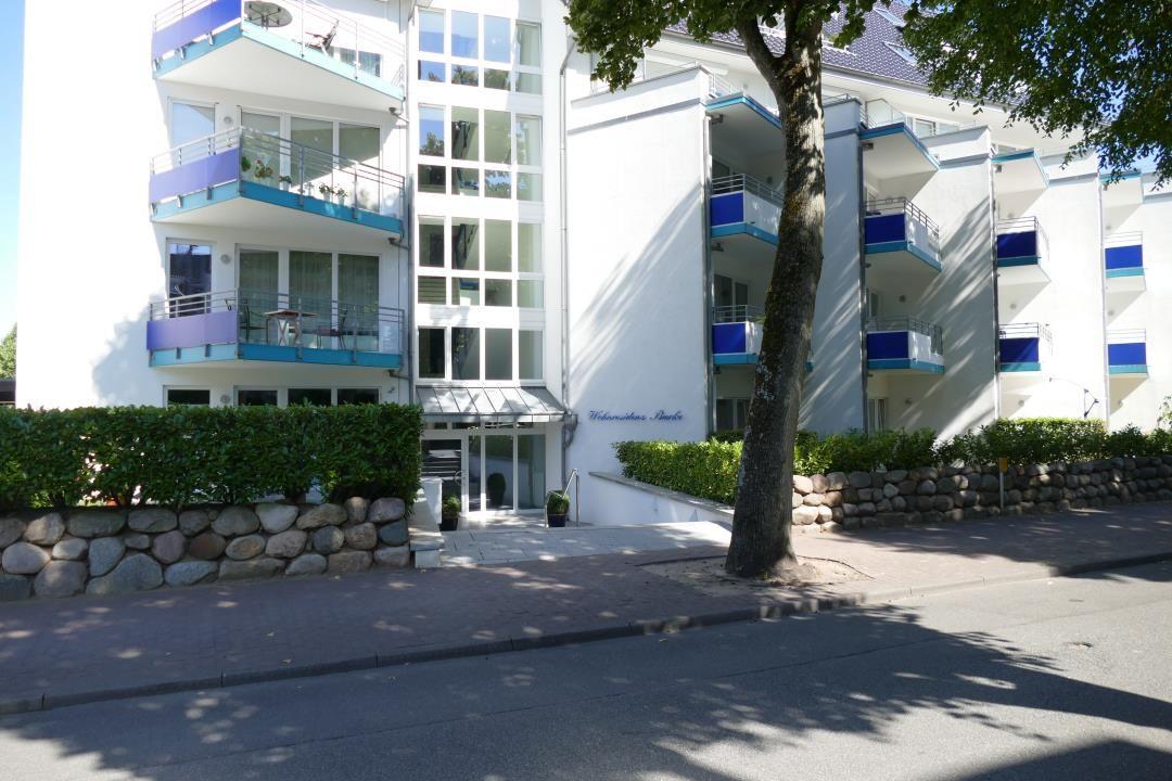 White multi-family house with balconies and entrance area.