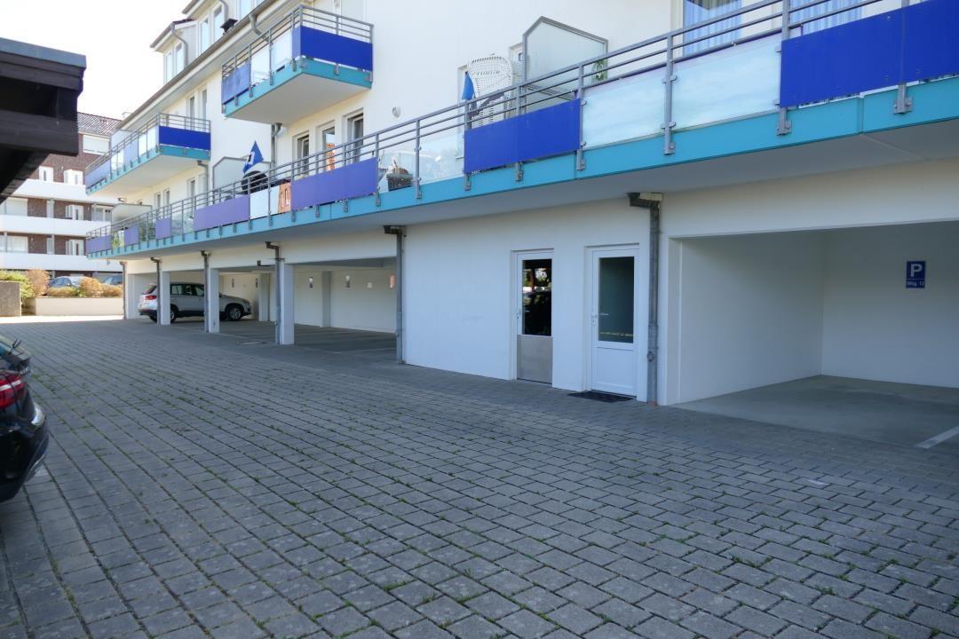 Building with balconies and parking spaces on the ground floor.