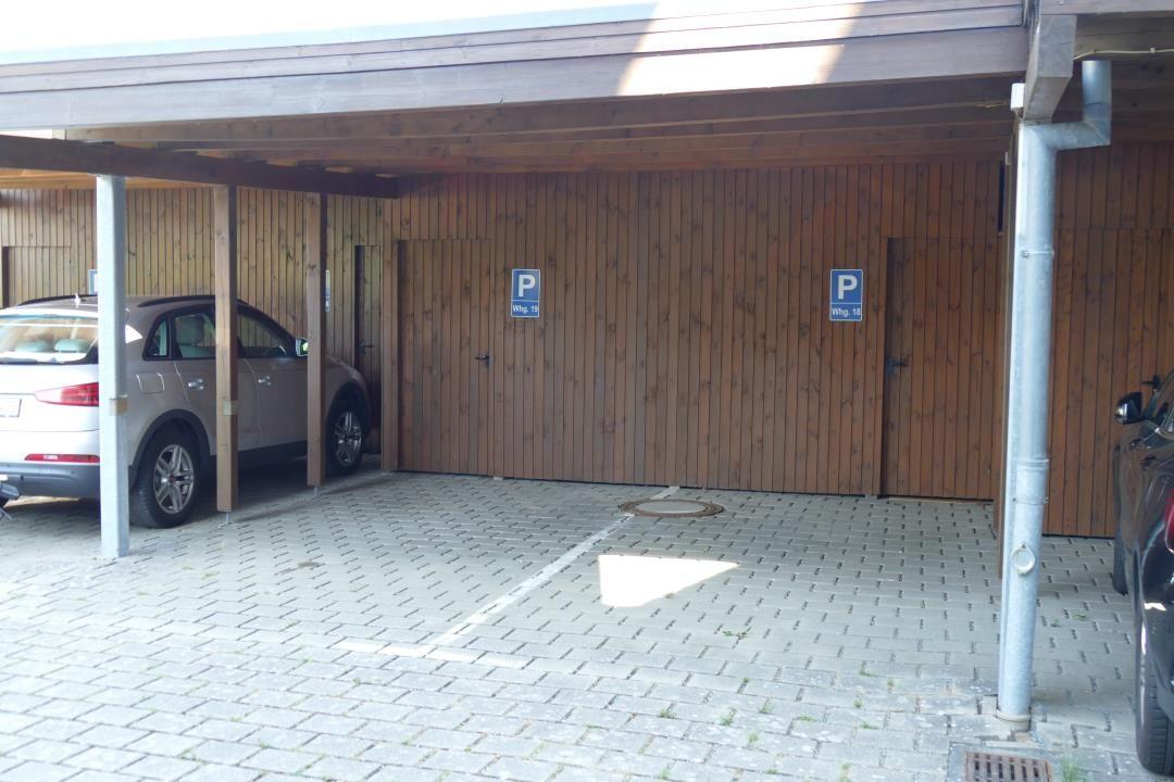 Parking area with wooden wall and two doors for apartments.
