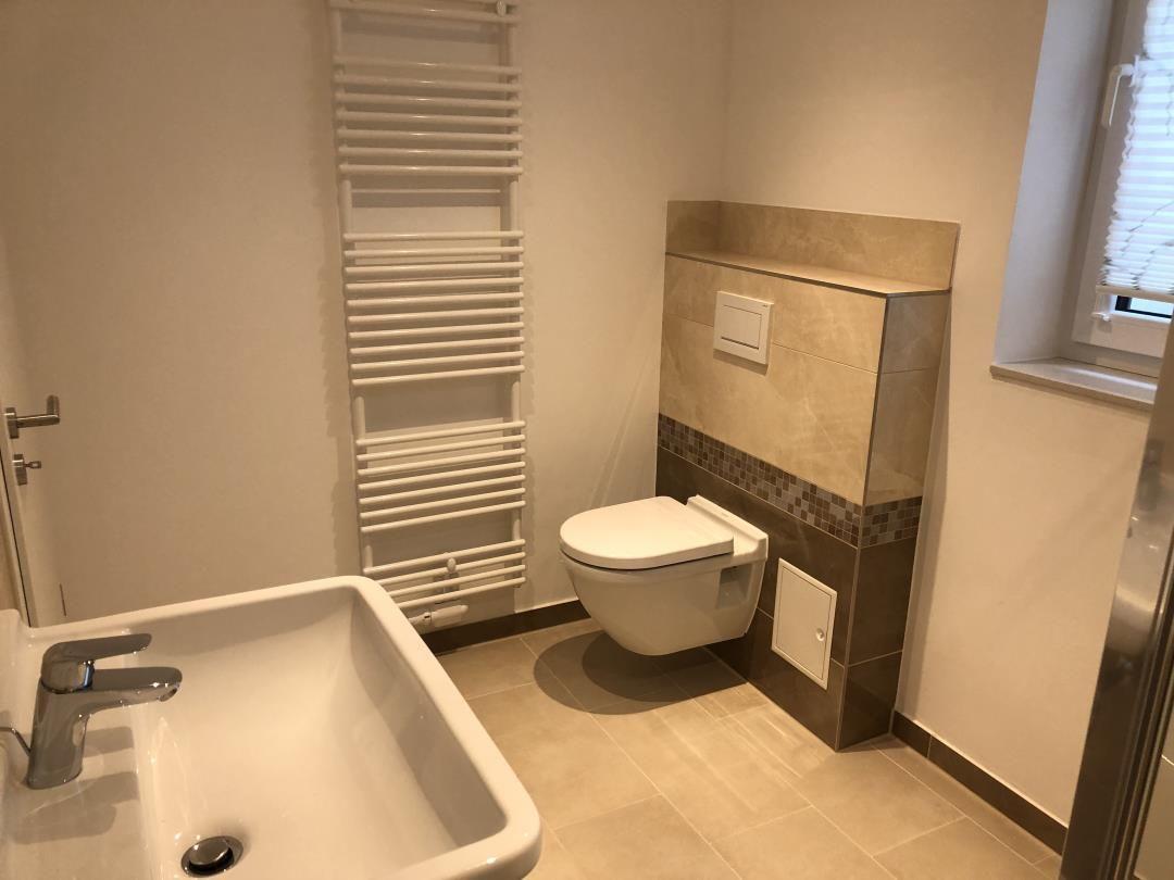 Badezimmer mit Waschbecken, Toilette und Heizkörper.