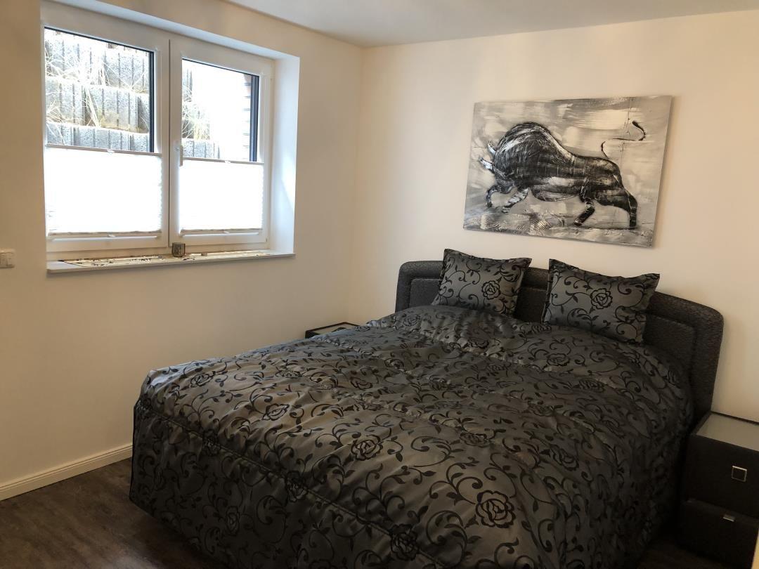 Schlafzimmer mit Bett, Fenster und Wandbild eines Stiers.