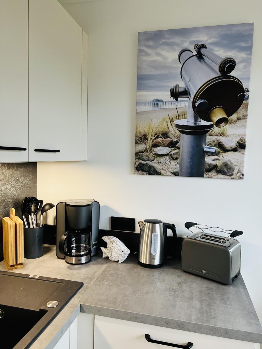 Kitchenette with coffee maker, kettle, and toaster. Wall art shows a telescope.