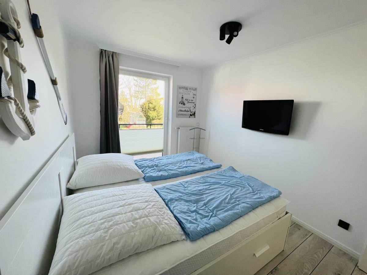 Bedroom with double bed, TV, and window to balcony.