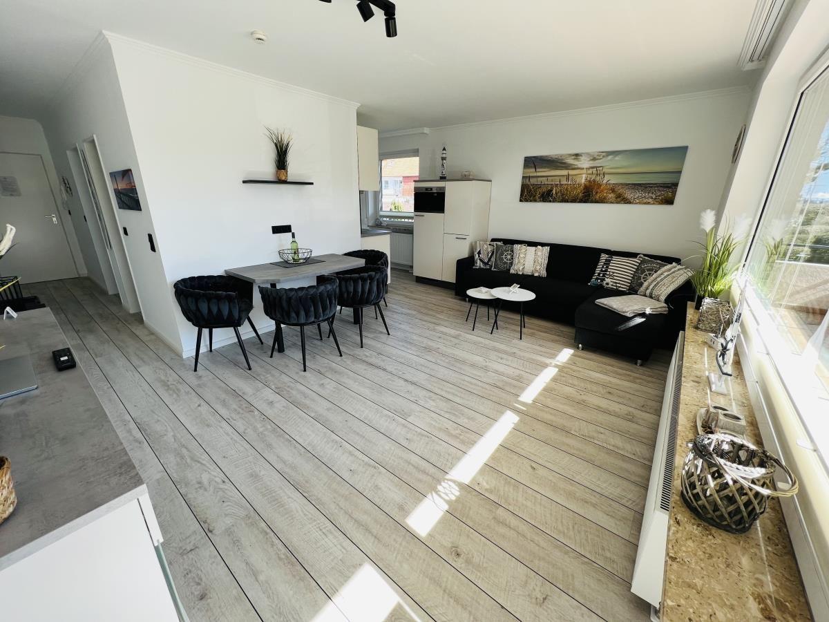 Living and dining area with sofa, table and chairs as well as kitchenette.