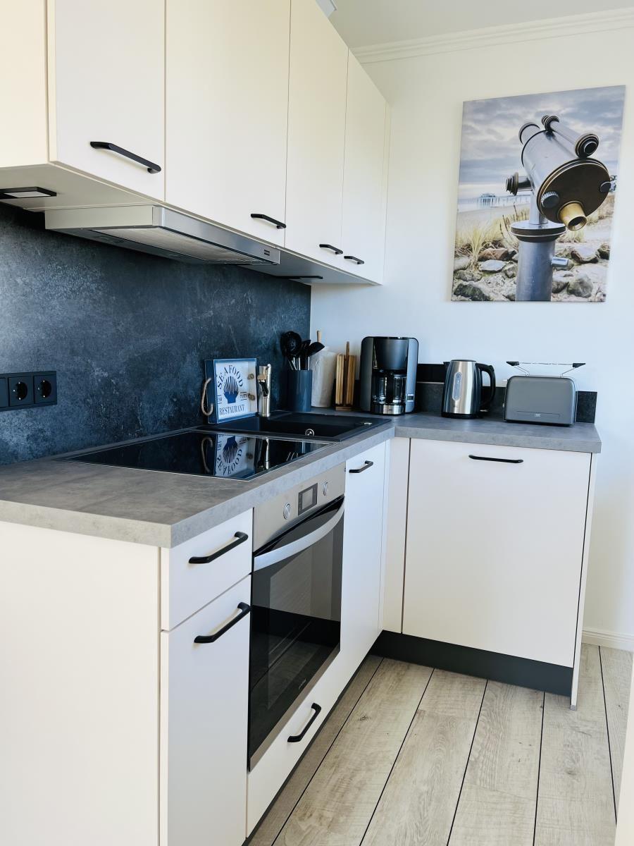 Modern kitchen with white cabinets, stainless steel appliances, and kitchen counter.
