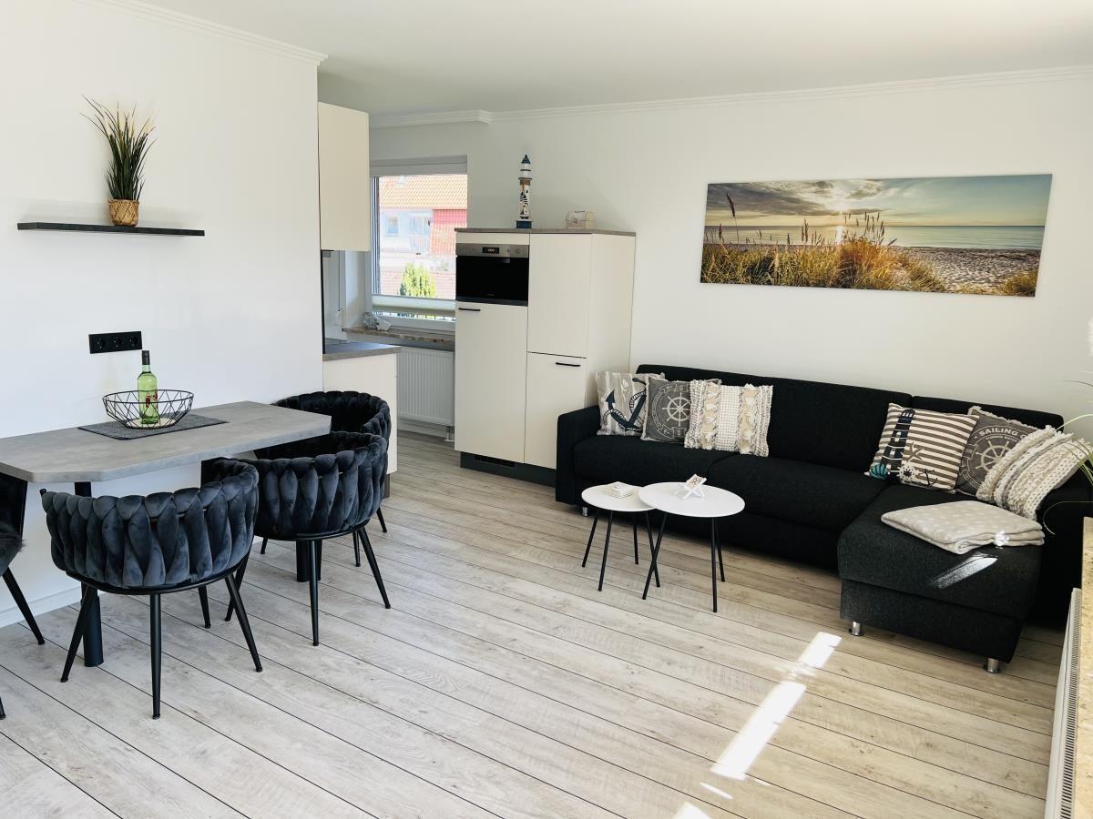 Living and dining area with sofa, table, and kitchenette.