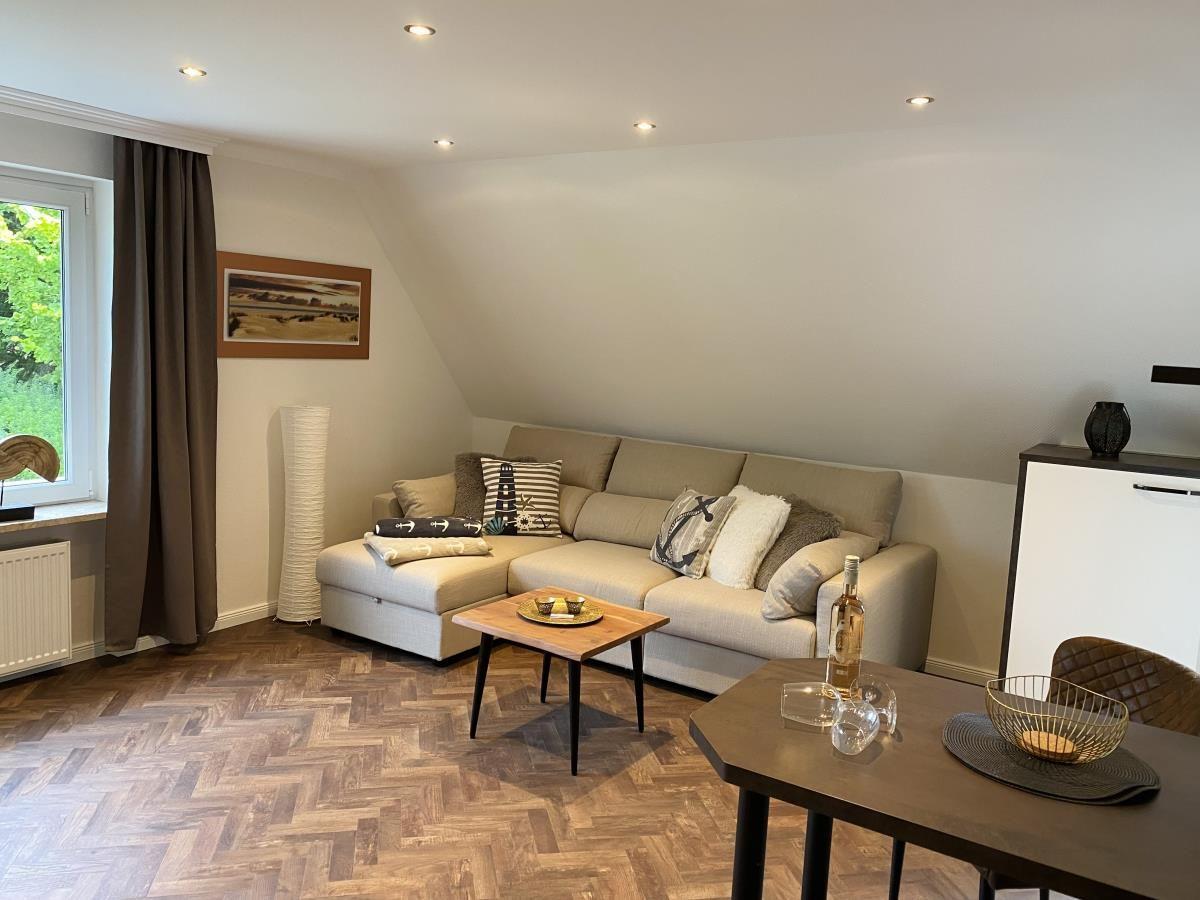 Wohn- und Essbereich mit Sofa, Holzboden und Fenster.