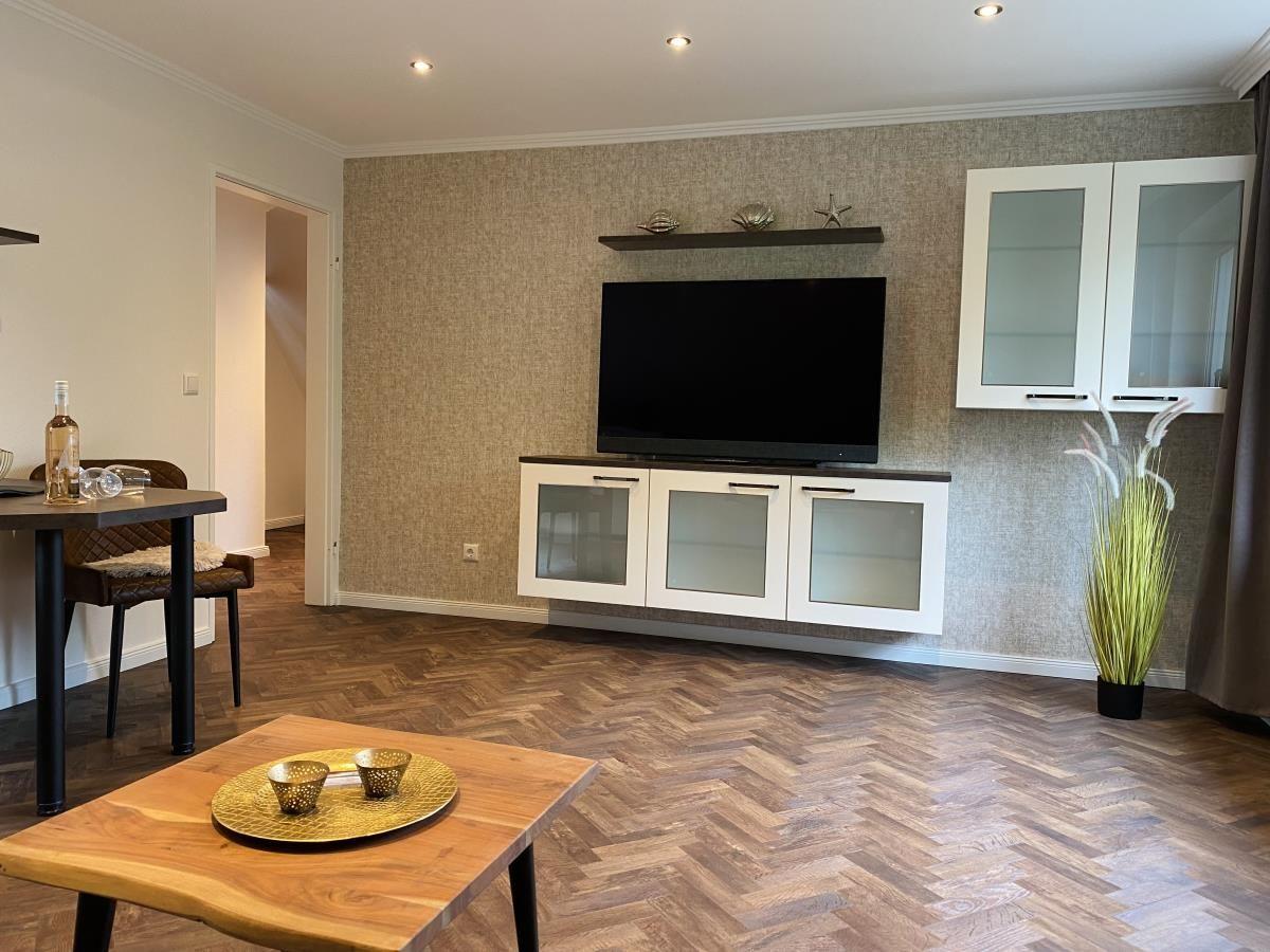 Wohnzimmer mit TV, Schrank und Holzboden