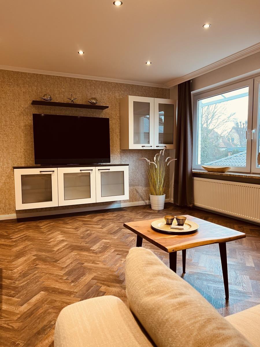 Wohnzimmer mit Holzboden, Fernseher und Fenster