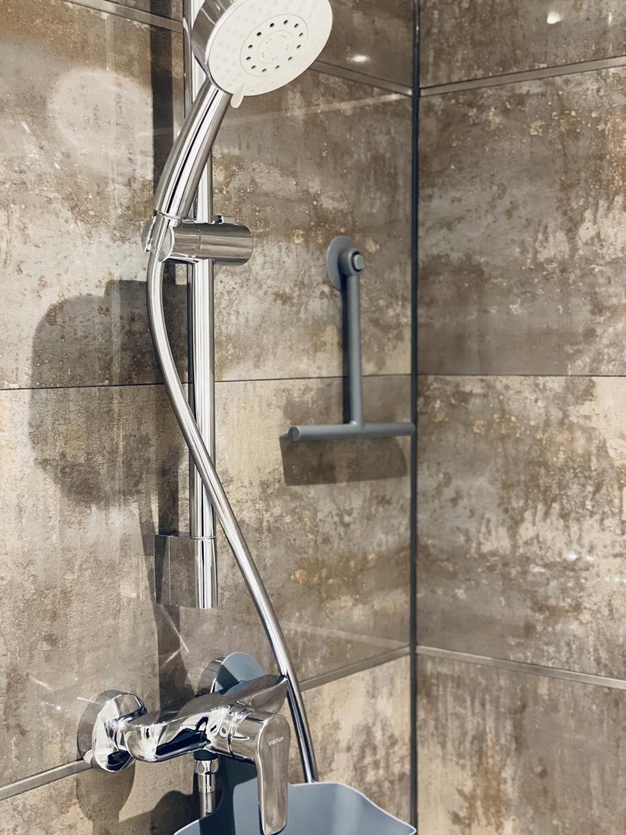 Duschkopf mit Handbrause und Wandhalterung in Dusche mit Steinfliesen