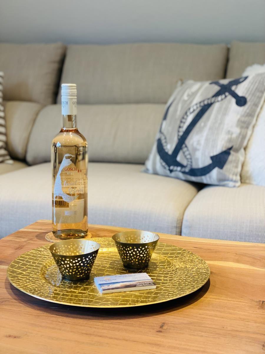 Auf dem Tisch steht eine Flasche Wein mit zwei Gläsern auf einem goldenen Tablett.