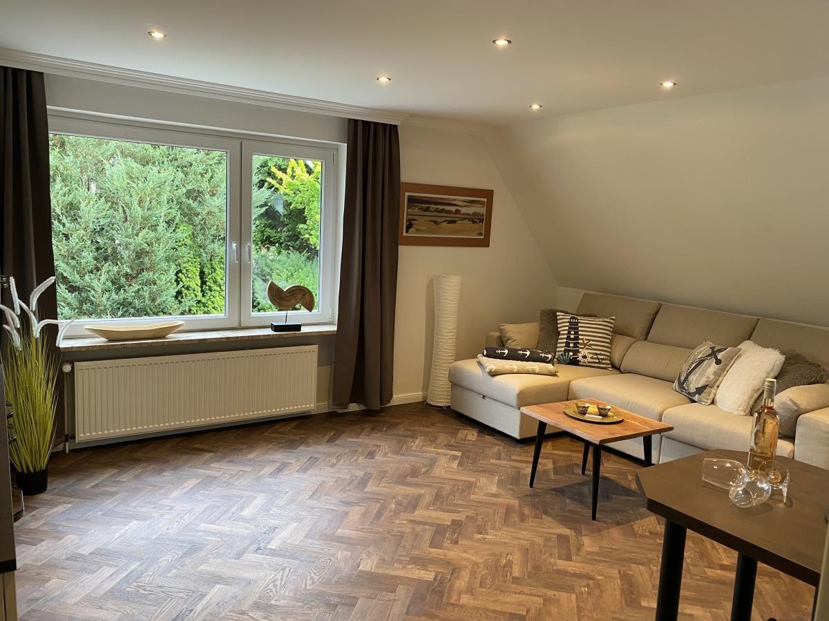 Wohnzimmer mit Sofa, Tisch und Fenster mit Blick auf Bäume.