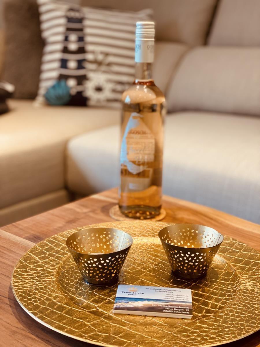 Auf dem Tisch steht eine Flasche Wein mit zwei Gläsern auf goldenem Tablett.