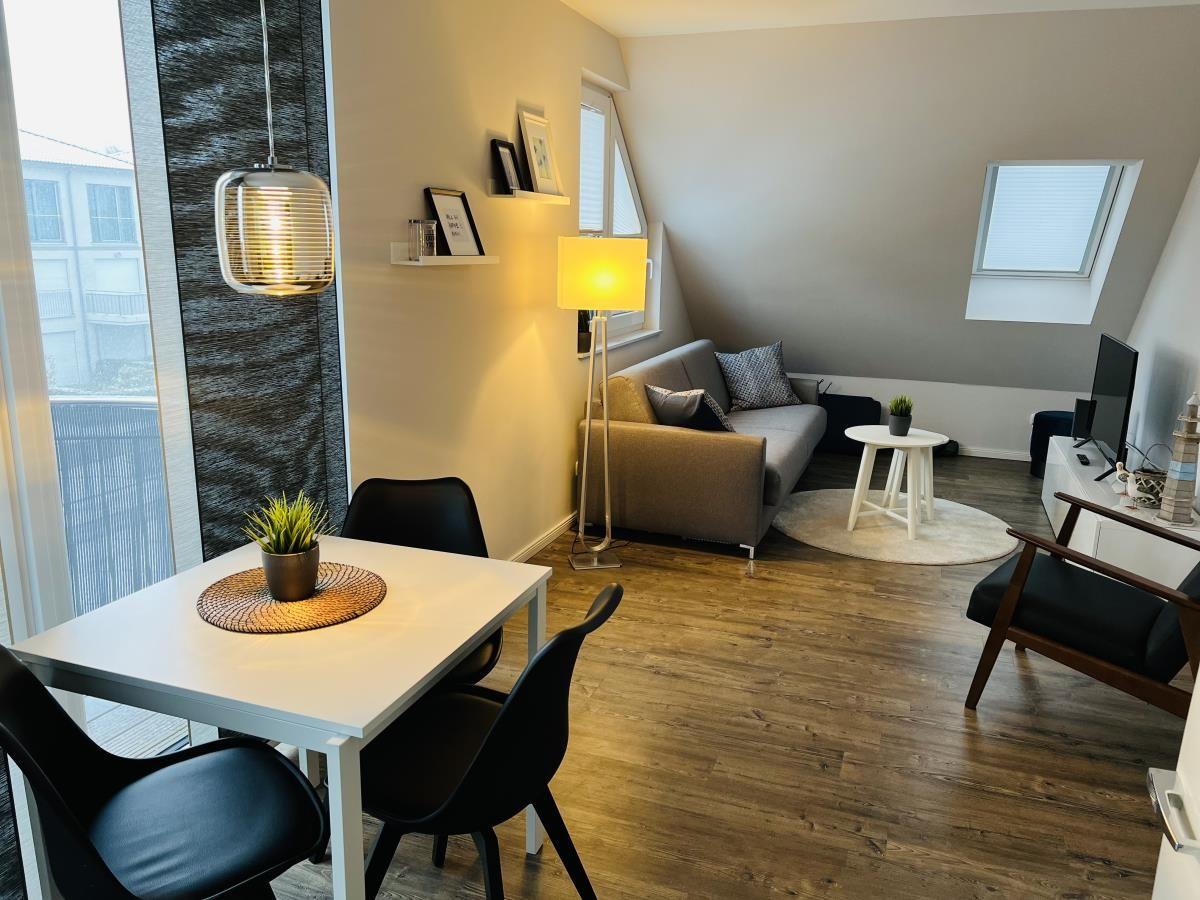 Wohnung mit Essbereich, Sofa und TV. Holzboden und große Fenster.