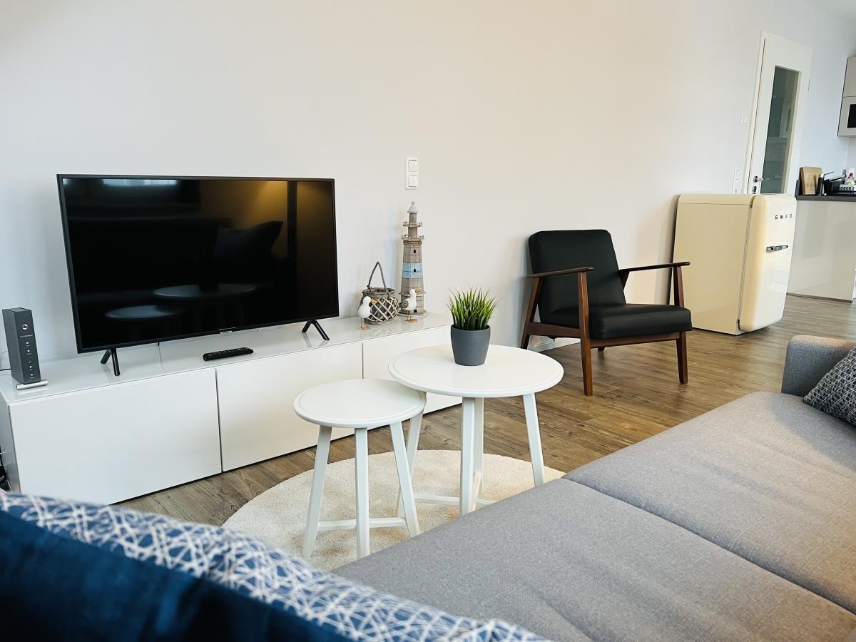 Wohnzimmer mit Sofa, Fernseher und Sitzgruppe.