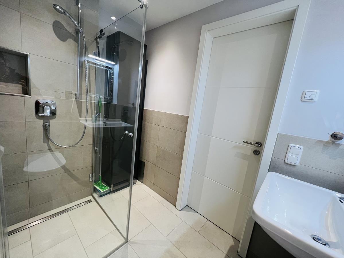 Badezimmer mit Dusche, Waschbecken und Tür