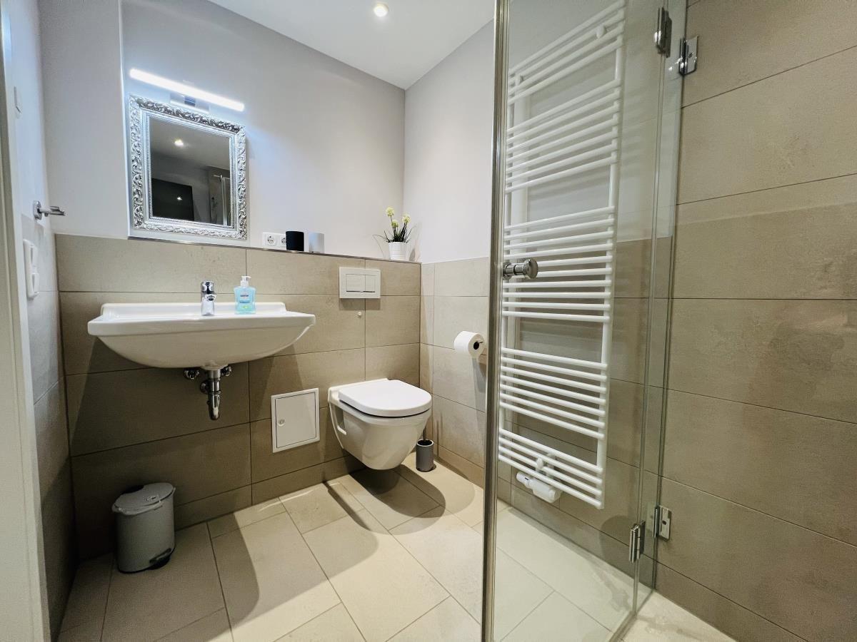 Badezimmer mit Dusche, Waschbecken und Toilette.