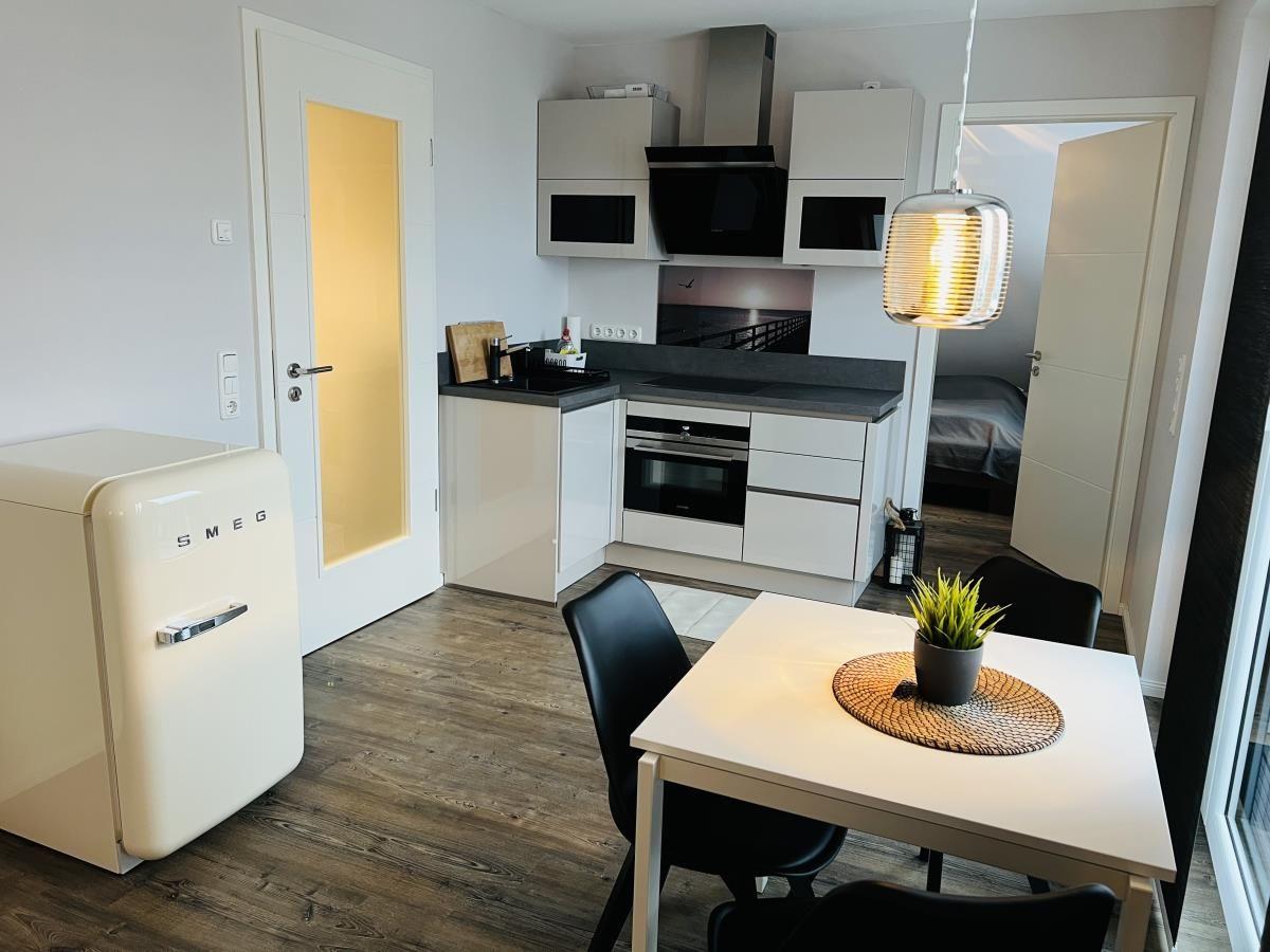 Küche mit Essbereich, weiße Schränke, schwarze Arbeitsfläche und Retro-Kühlschrank.