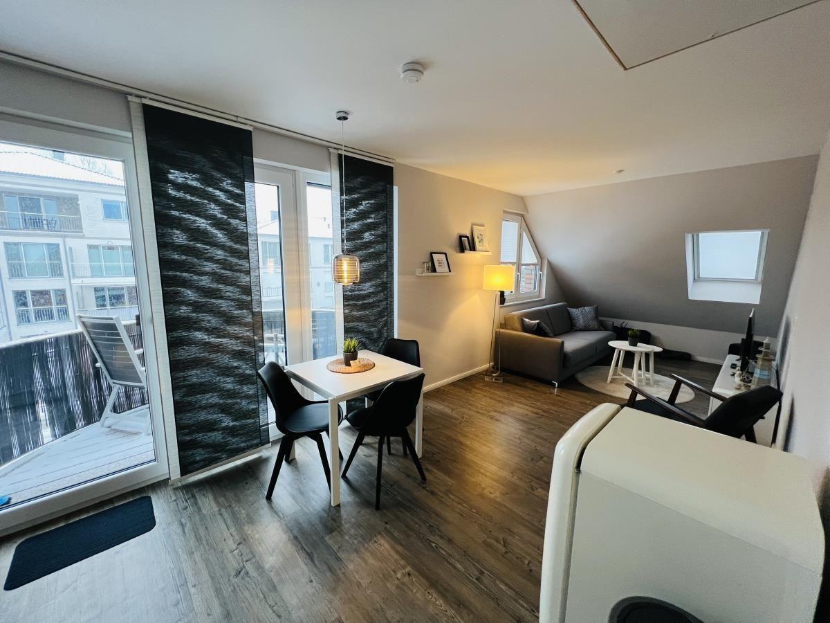 Wohnbereich mit Essbereich, Sofa und Balkon. Holzboden und große Fenster.