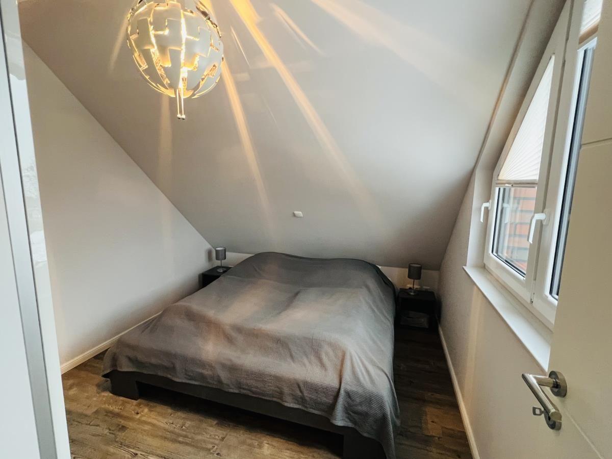 Schlafzimmer mit Dachschrägen, Bett, Nachttischen und Fenster.