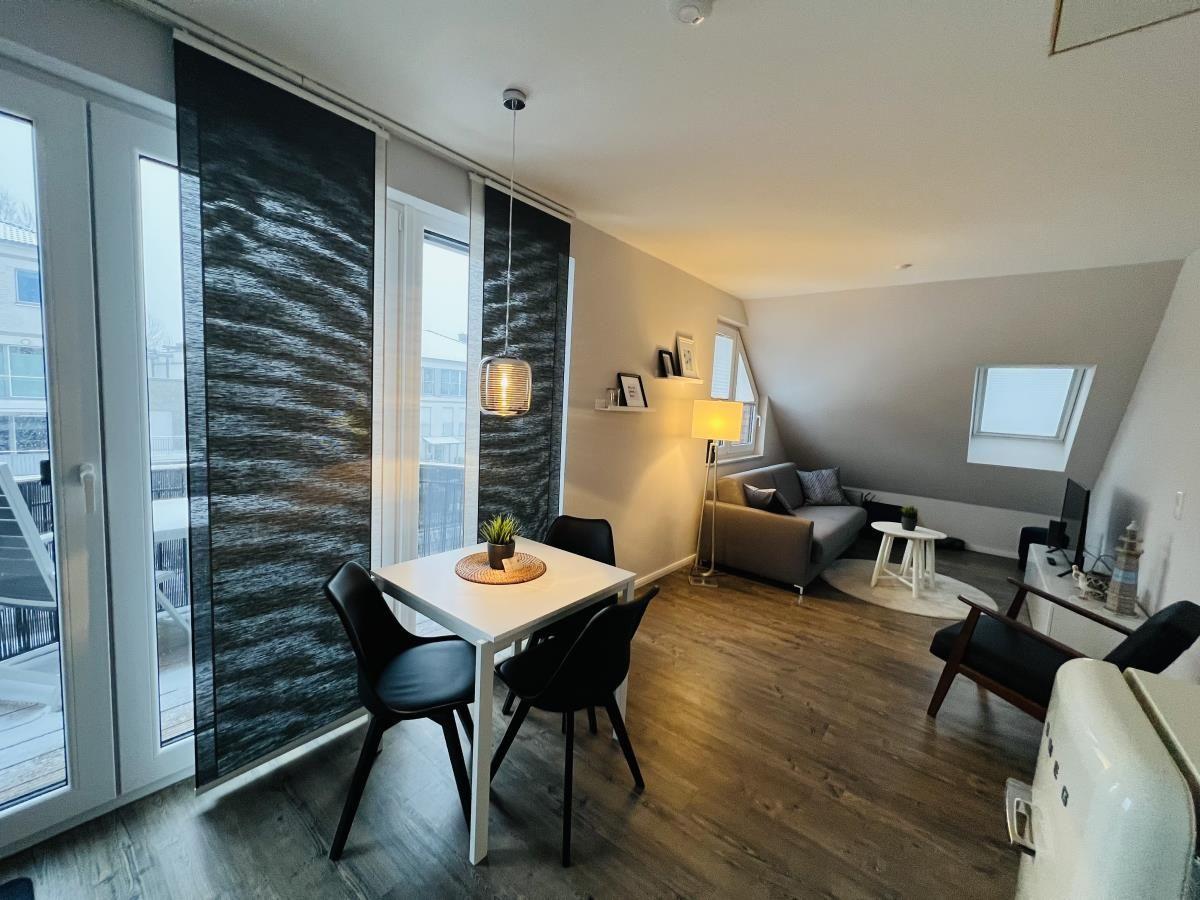 Wohnung mit Essbereich, Sofa und Balkon. Holzboden und große Fenster.