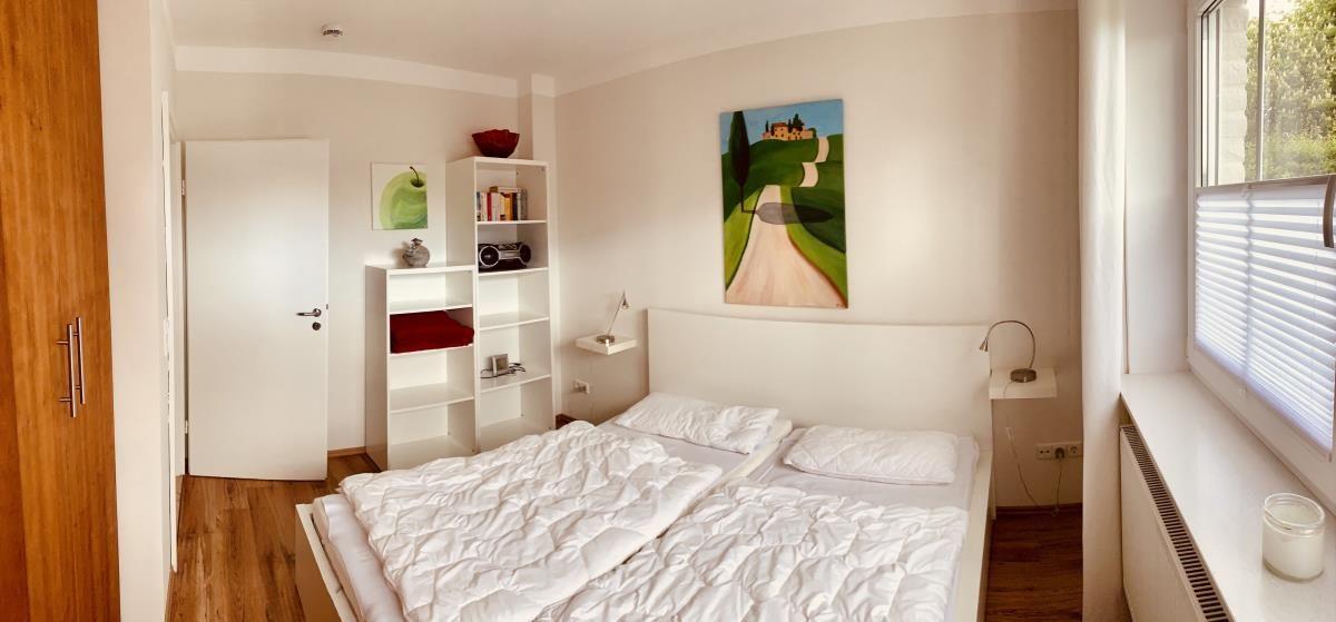 Bedroom with double bed, shelf, and window with blinds.