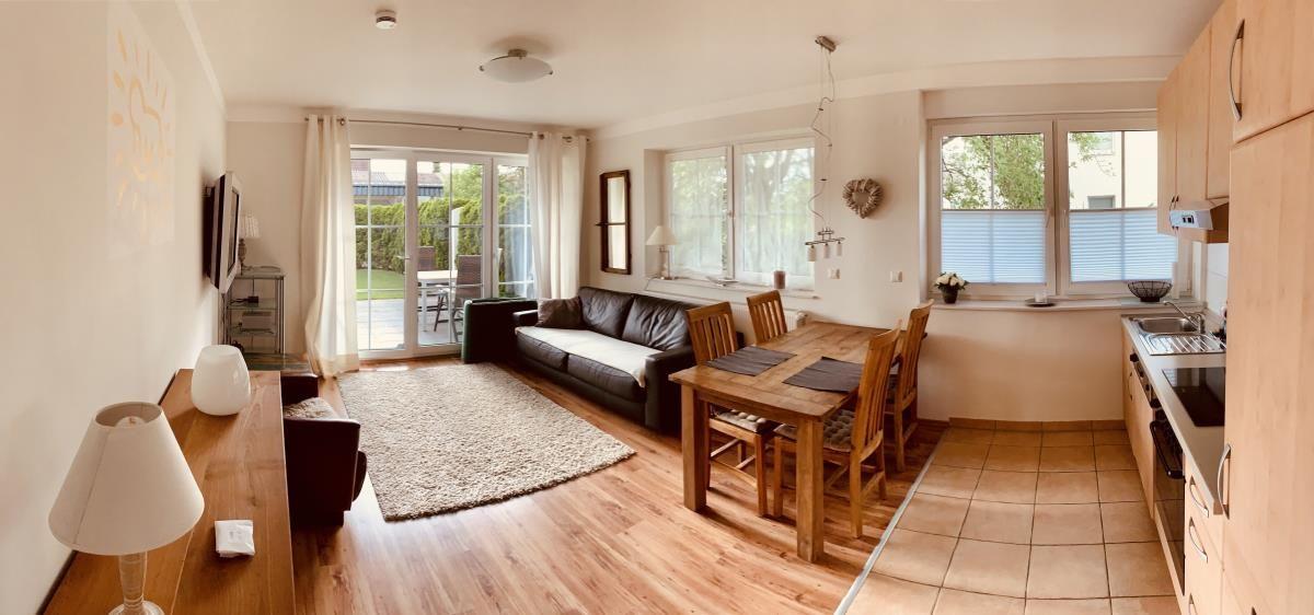 Living and dining area with kitchen, sofa, dining table, and terrace door.
