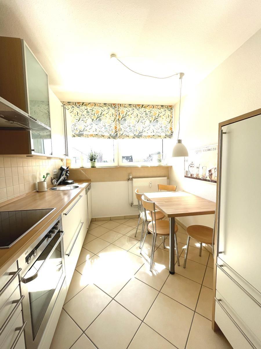 Küche mit Esstisch, Fenster und Küchengeräten.