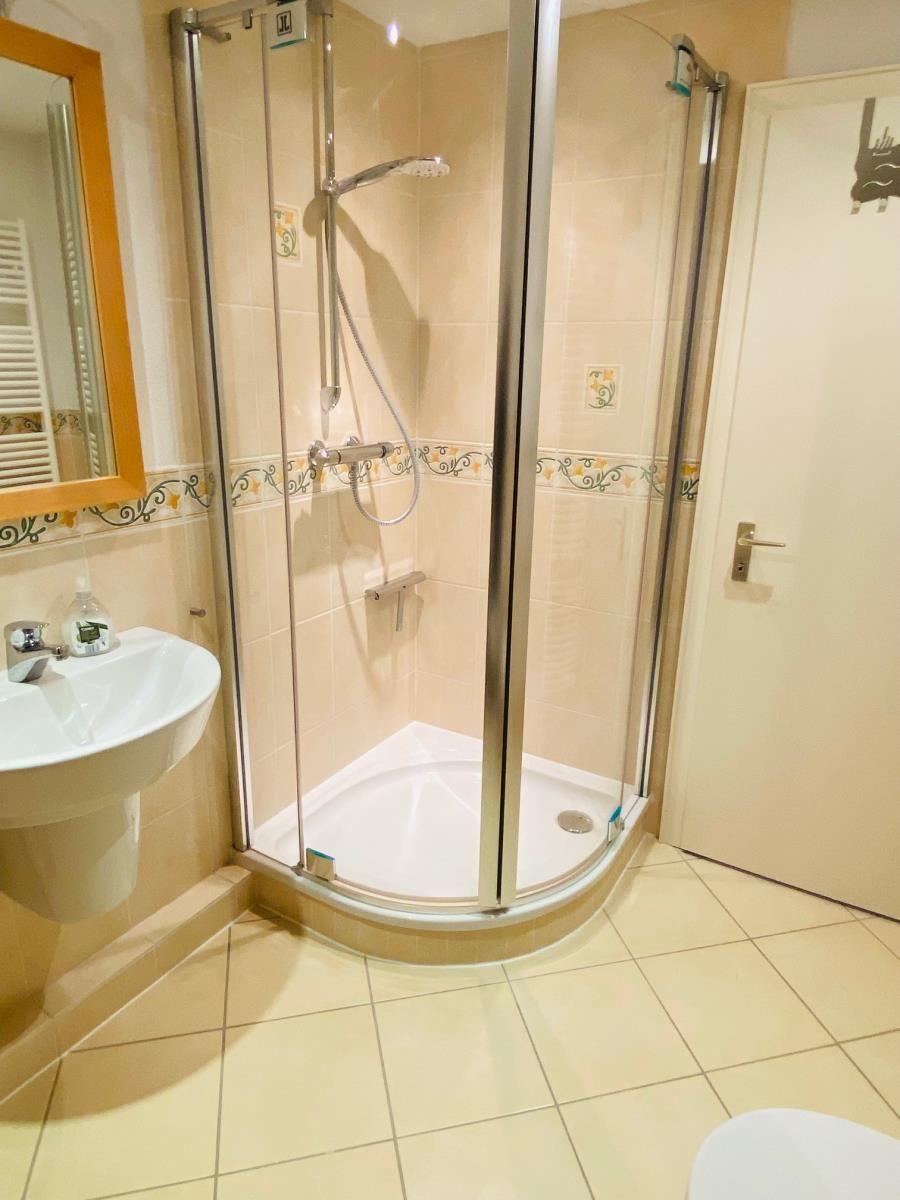 Badezimmer mit Duschkabine, Waschbecken und Spiegel