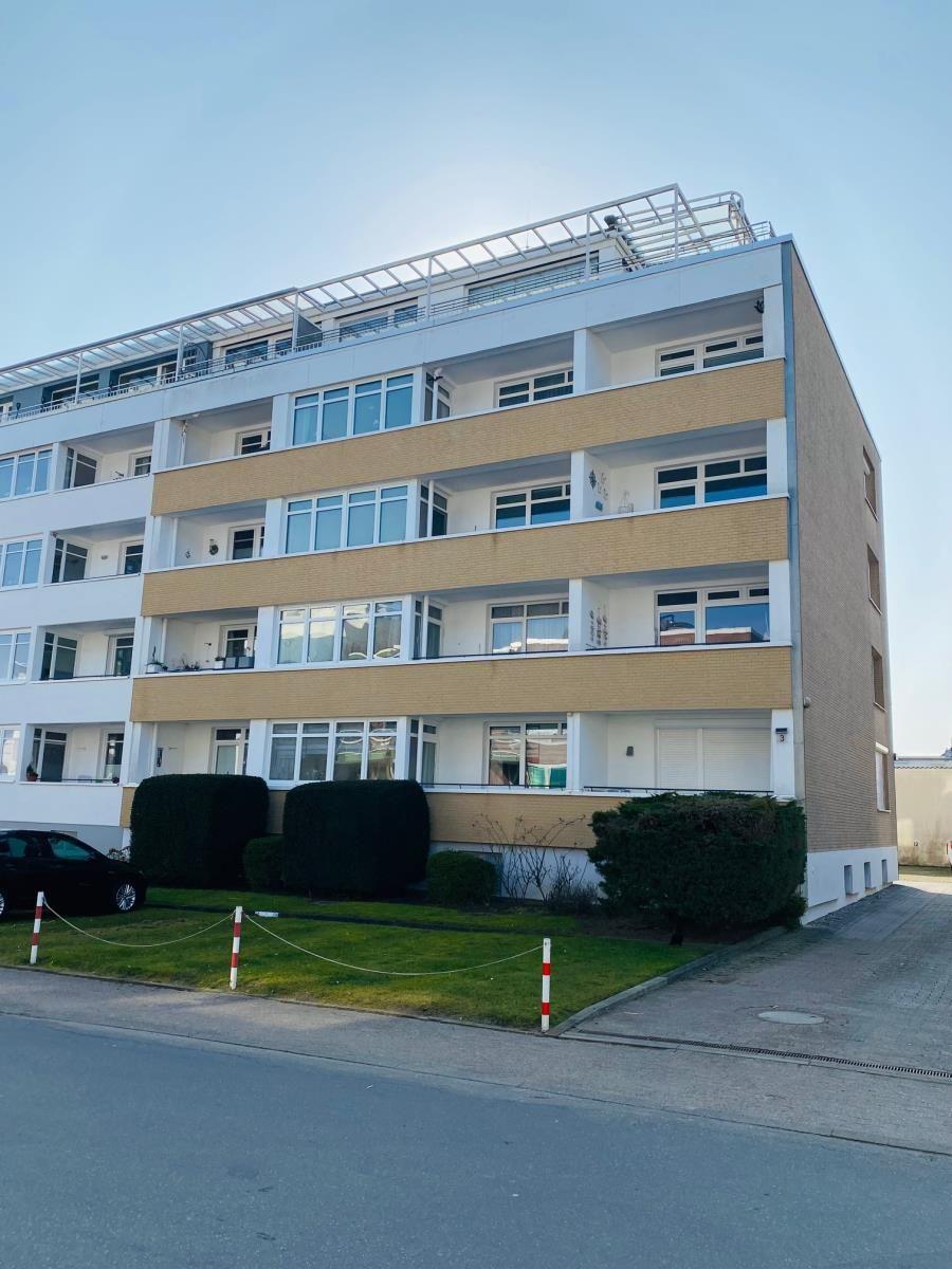 Modernes Mehrfamilienhaus mit Balkonen und grüner Umgebung.