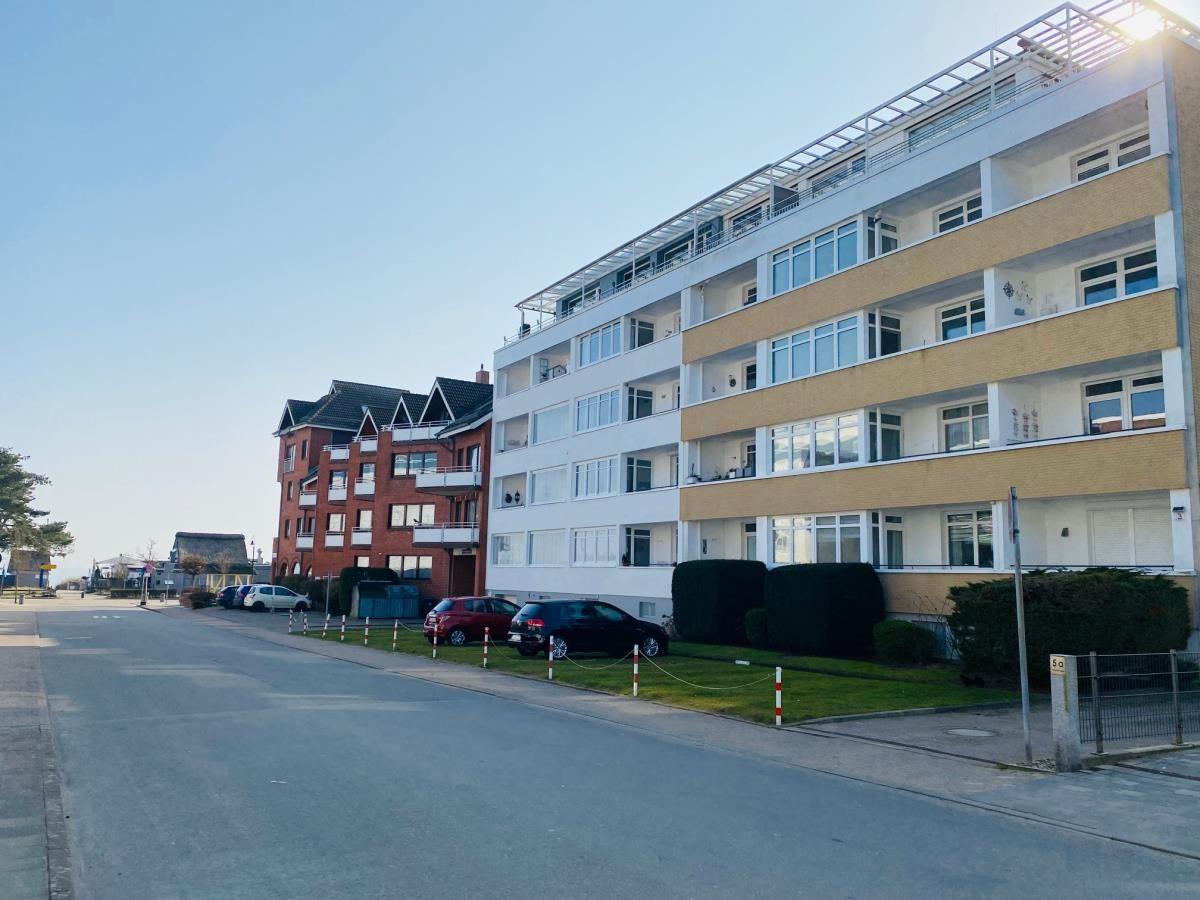 Wohnhaus mit Balkonen und gepflegtem Grünstreifen entlang der Straße.