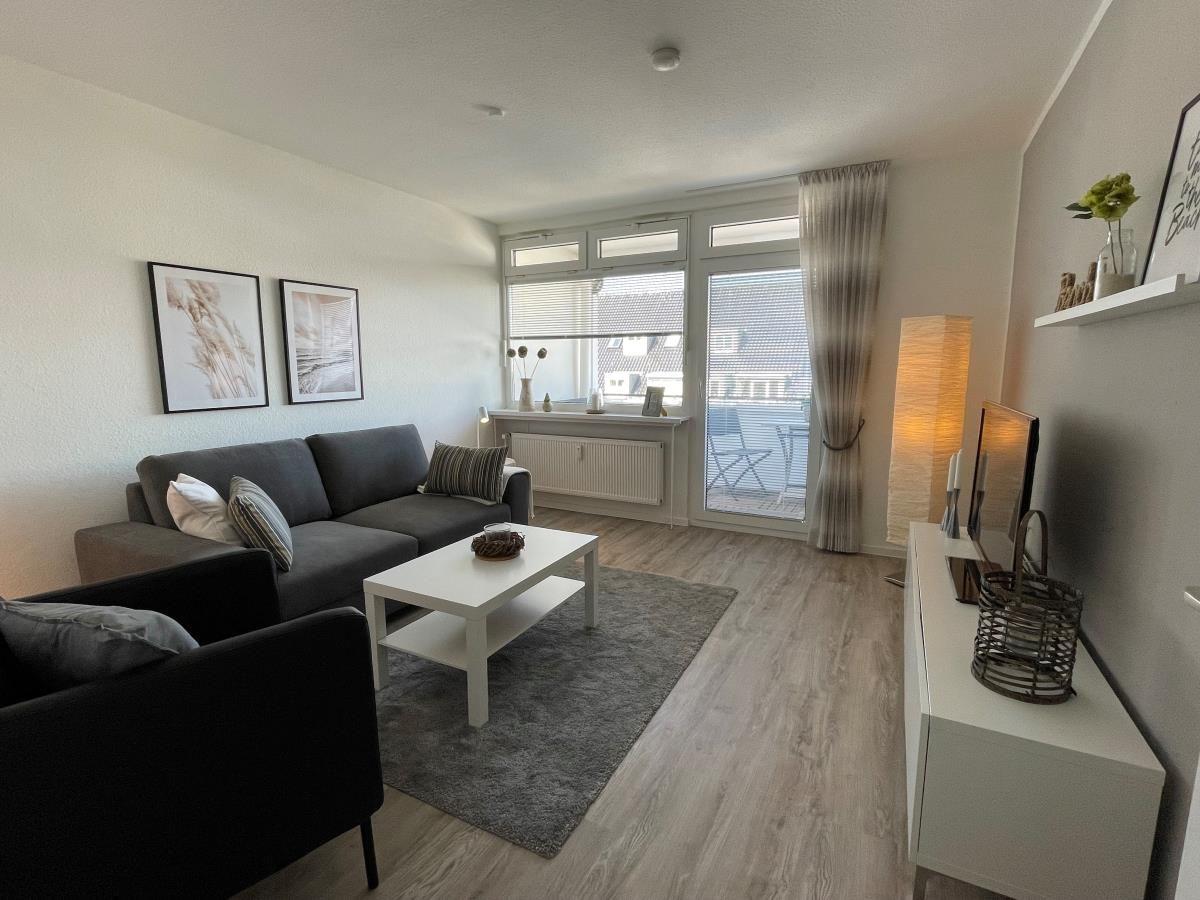 Wohnzimmer mit Sofa, Couchtisch und Balkonansicht.
